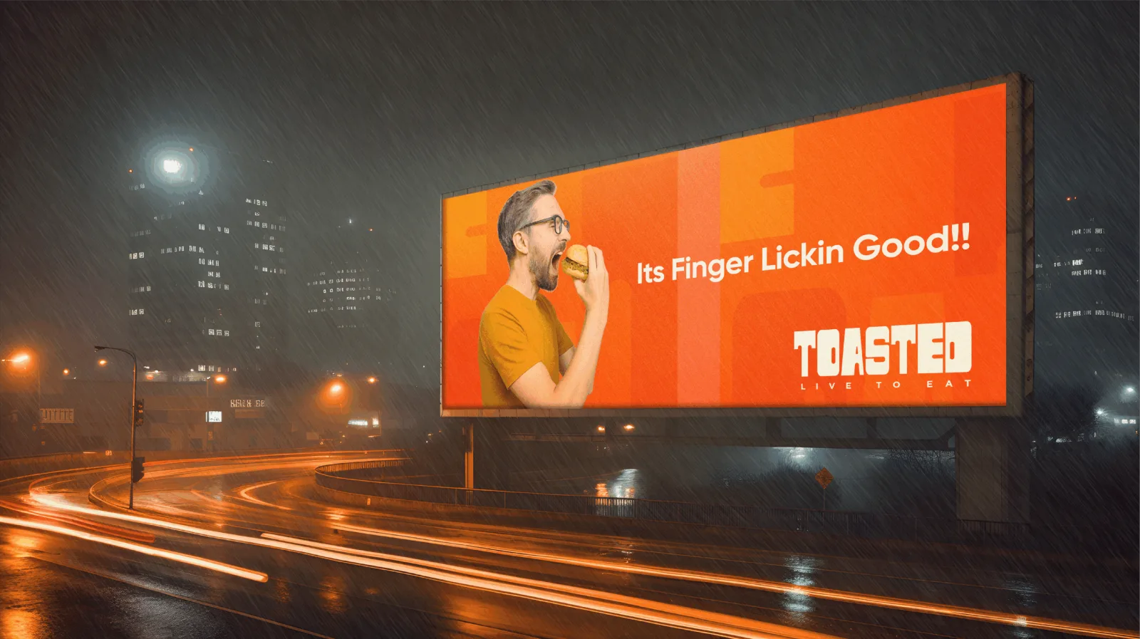 A Toasted highway billboard at night showing a man biting a burger, "It's Finger Lickin Good"